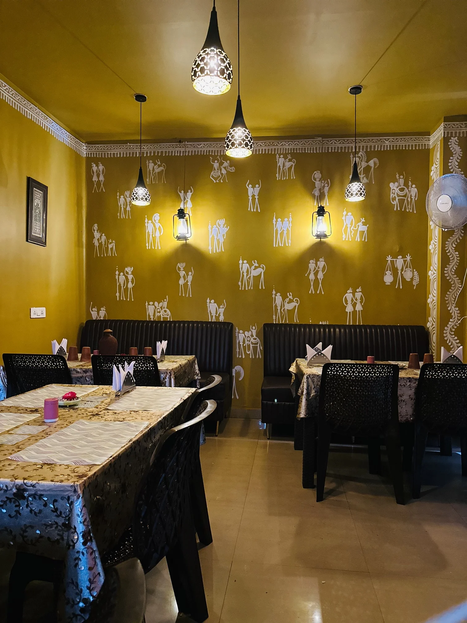 JOMHA Restaurant elegant dining area with golden Warli art walls and traditional decor
