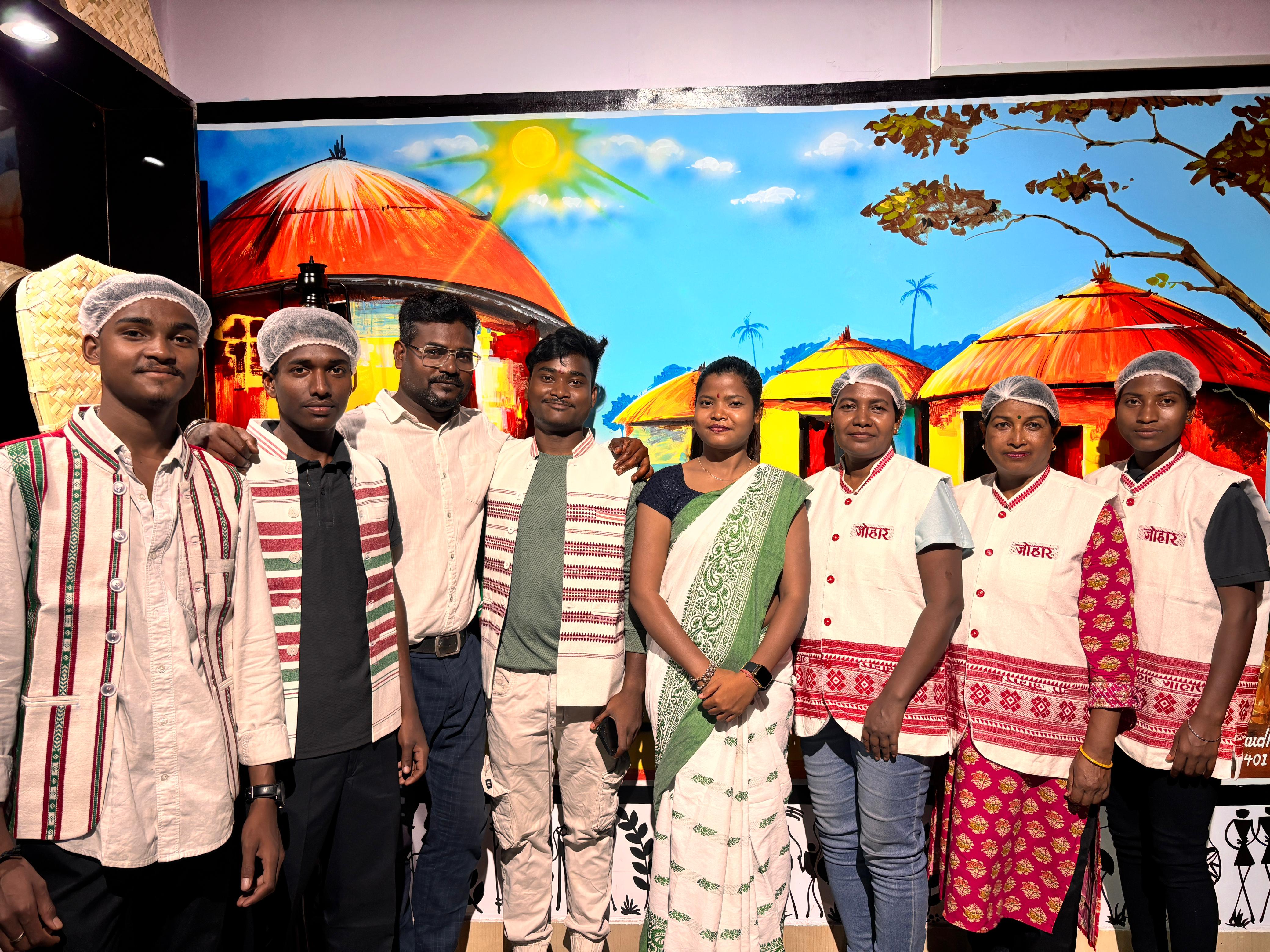 JOMHA Restaurant team in traditional attire with tribal mural
